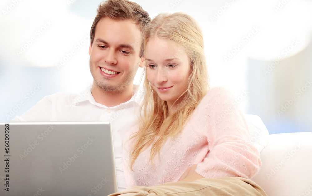 Couple using a laptop and smiling Couple using a laptop and smiling