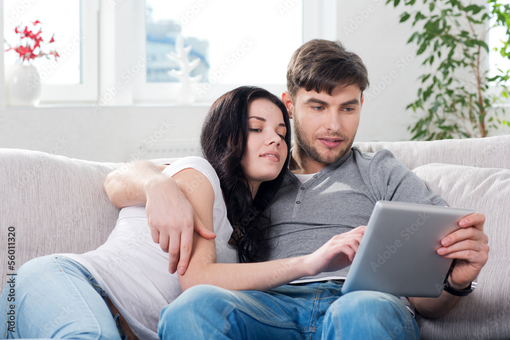 couple sitting on a couch with tablet computers couple sitting on a couch with tablet computers