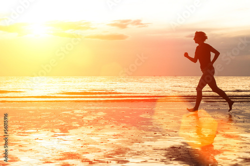 Young woman jogging on the beach at sunset.