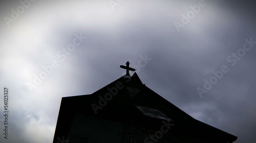 Sinister vision of a cross atop the church in cloudy day