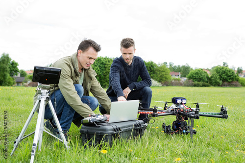 Technicians Using Laptop By Tripod And UAV