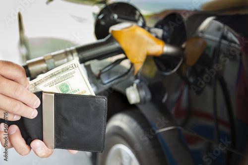 man counting money with gasoline refueling car at fuel station
