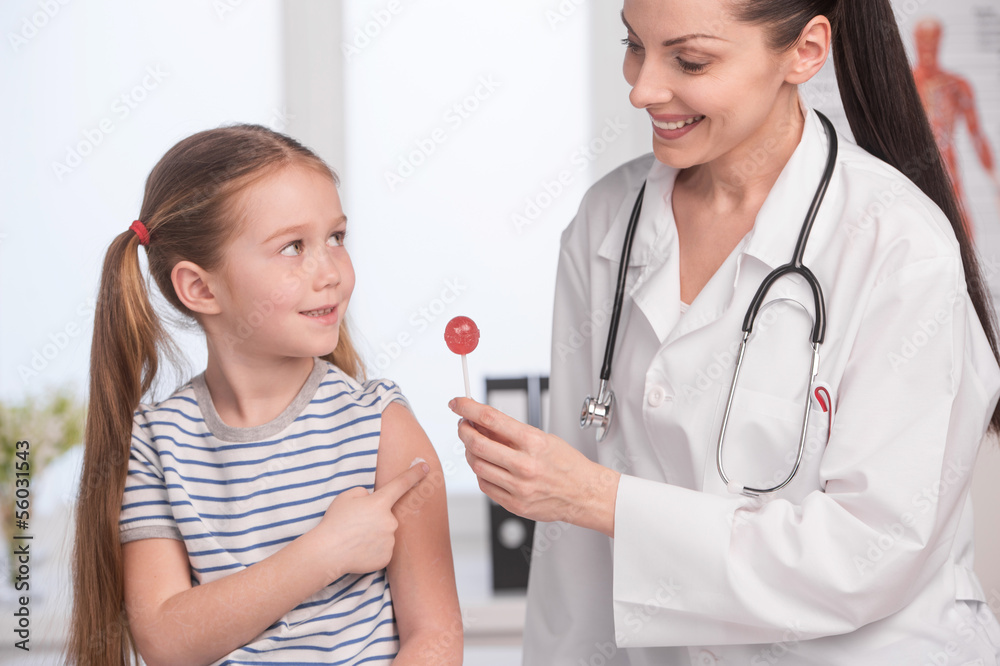 Doctor and little patient. Cheerful young doctor in lab coat giv Doctor and little patient. Cheerful young doctor in lab coat giv