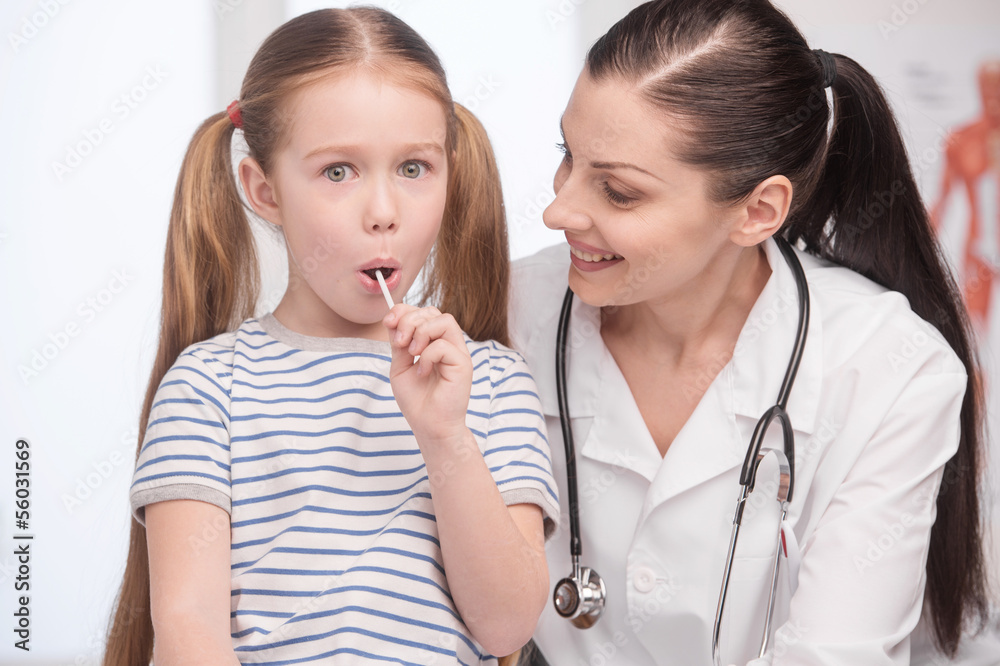 Doctor and little patient. Little girl with lollipop looking at
