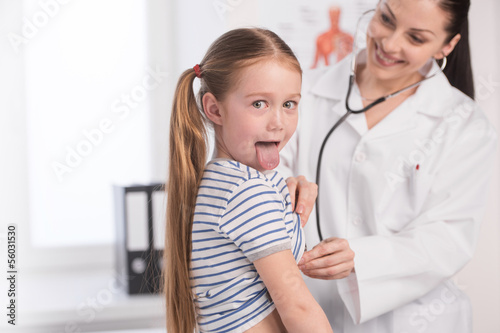 Doctor and little girl. Cheerful young doctor in lab coat examin