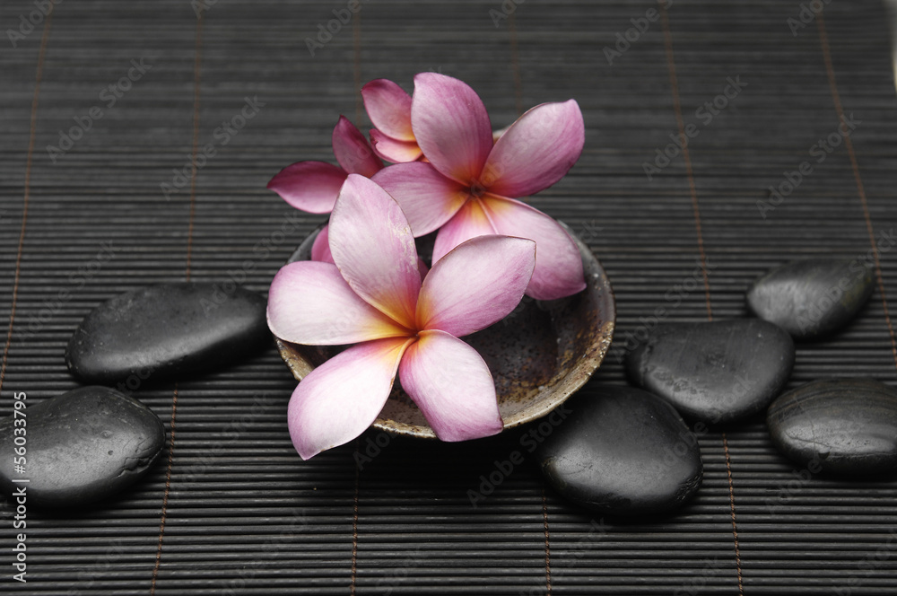 frangipani flower in wooden bowl with pebble on bamboo mat frangipani flower in wooden bowl with pebble on bamboo mat
