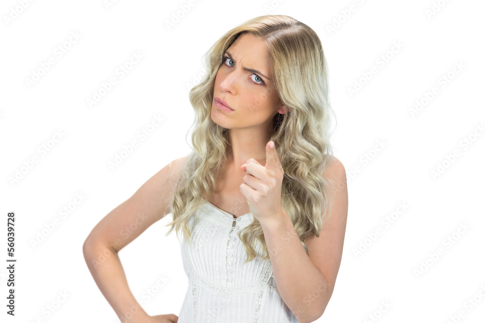 Frowning model in white dress pointing at camera