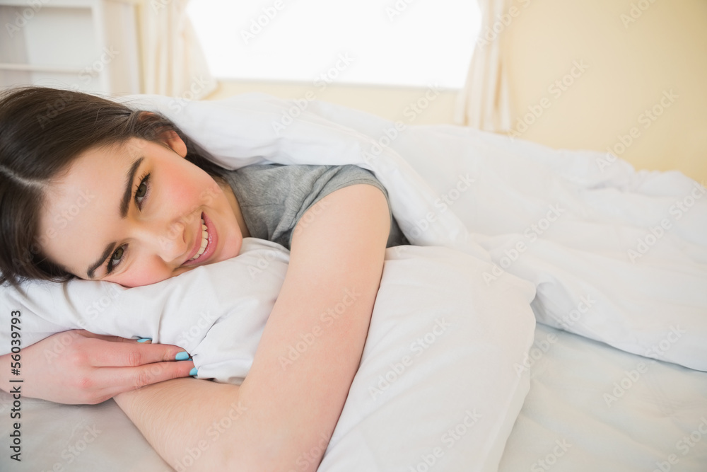 Happy brunette relaxing in her bed