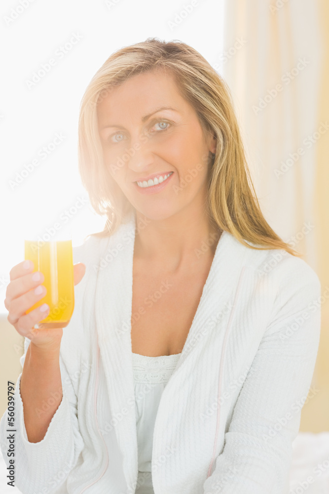 Content woman looking at camera enjoying a glass of orange juice Content woman looking at camera enjoying a glass of orange juice