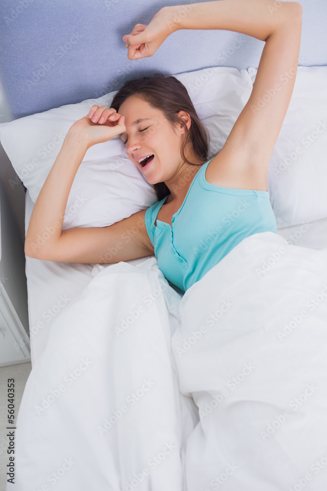 © WavebreakMediaMicro - Well rested brunette woman stretching and yawning in bed
