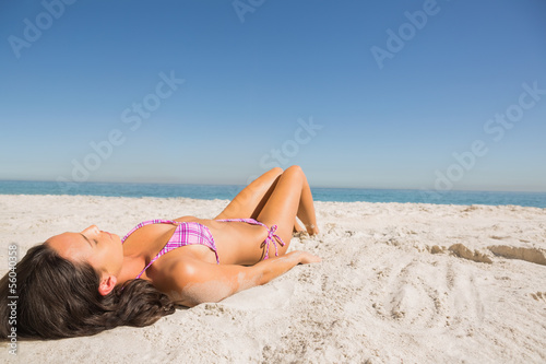 Beautiful young brunette in pink bikini sunbathing