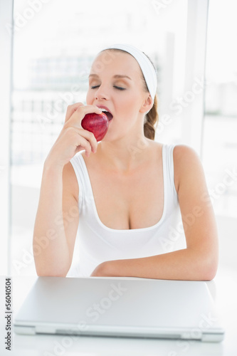 Calm pretty sportswoman eating an apple