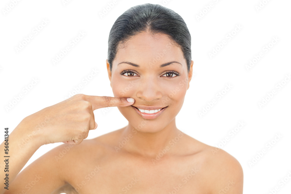 Smiling black haired model pointing above her lips
