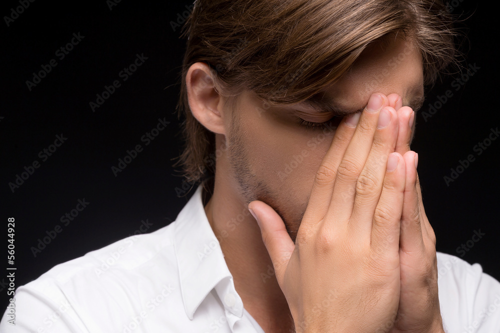 Frustrated man. Portrait of young men covering his face with han Frustrated man. Portrait of young men covering his face with han