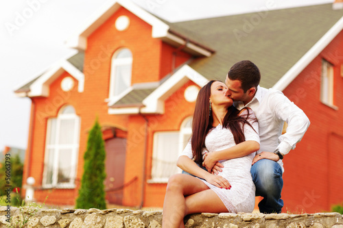 Happy couple kissing in front of new home