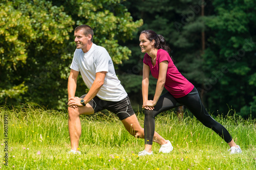 Female and male runner stretching outdoors