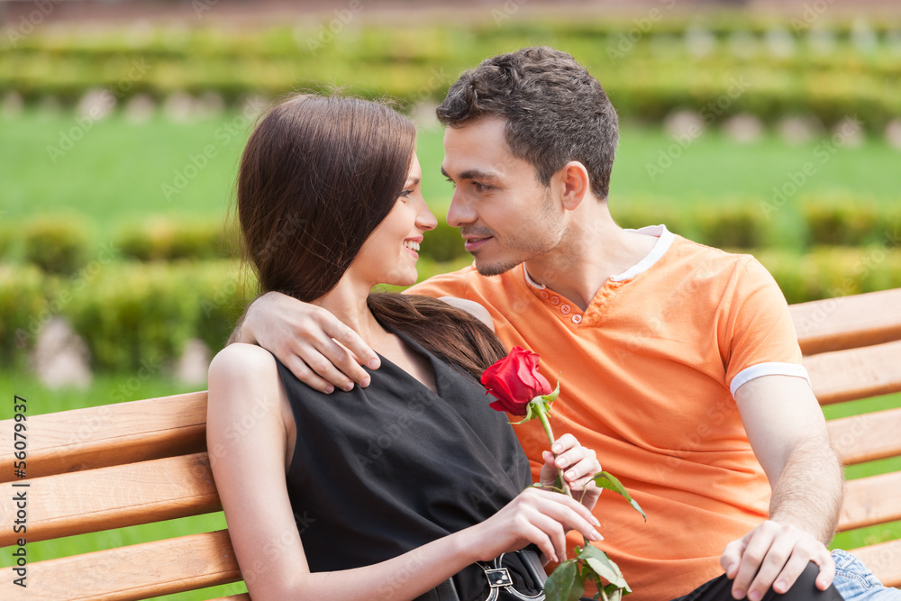 Fototapeta premium Loving couple on the bench. Beautiful young couple sitting close