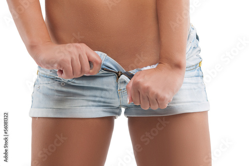 Woman in shorts. Woman in jeans shorts undressing while standing