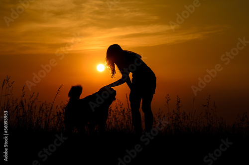 girl petting her dog in the sunset