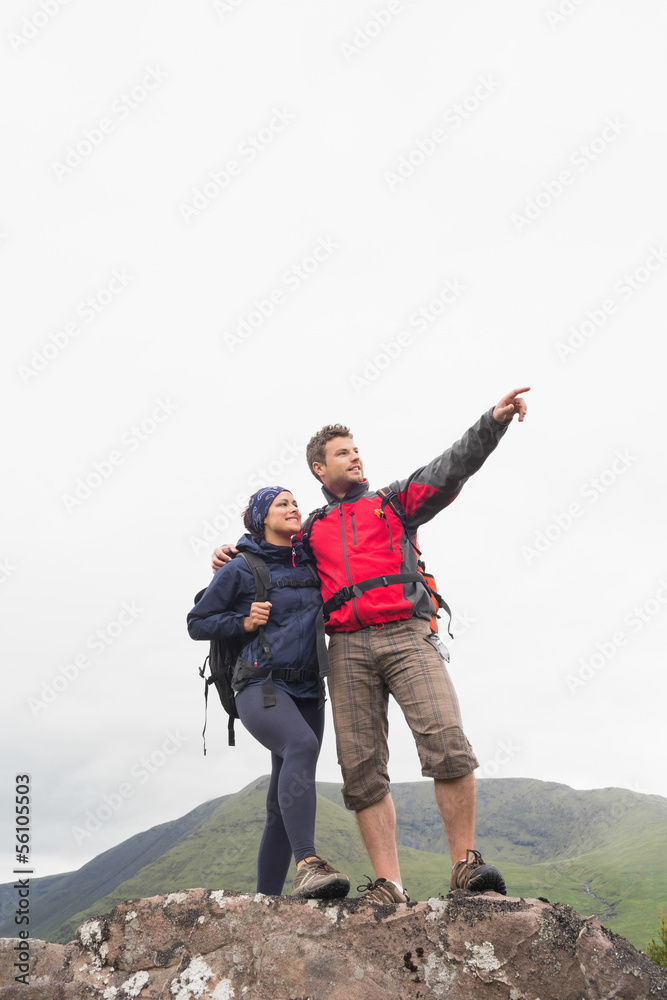 Couple standing on a rock looking up at the mountains Couple standing on a rock looking up at the mountains