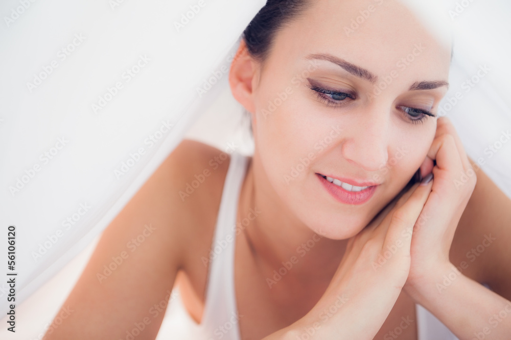 Happy brunette lying under the sheets looking down Happy brunette lying under the sheets looking down