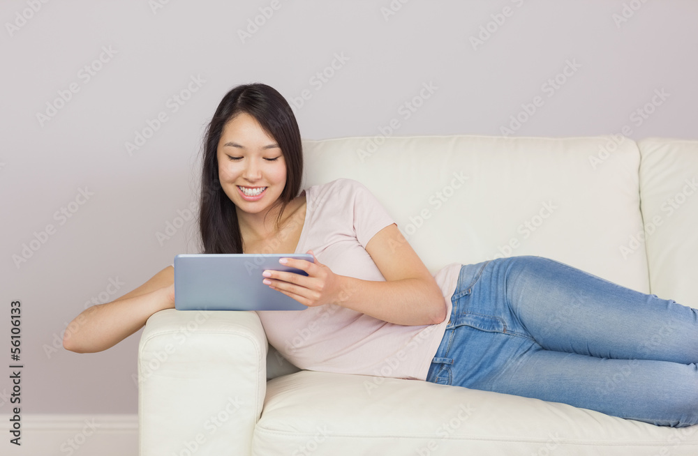 Pretty asian girl lying on the sofa using digital tablet Pretty asian girl lying on the sofa using digital tablet