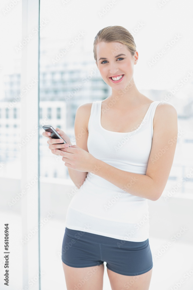 Smiling sporty woman text messaging