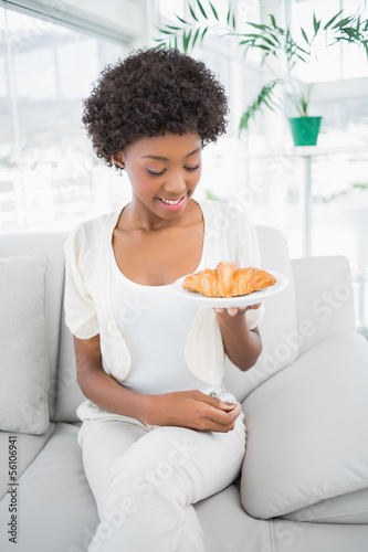 Smiling pretty brunette holding croissant