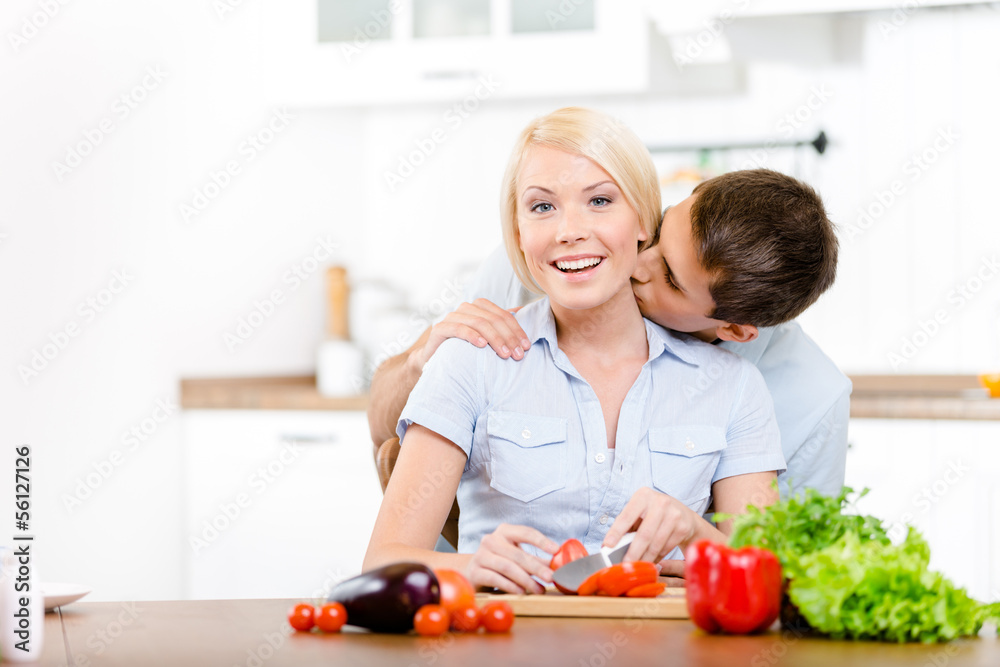 Man kisses girl while she is cooking 