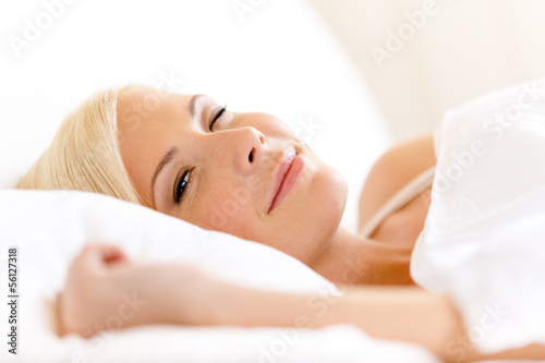 Close up of lying in bed woman on white pillow
