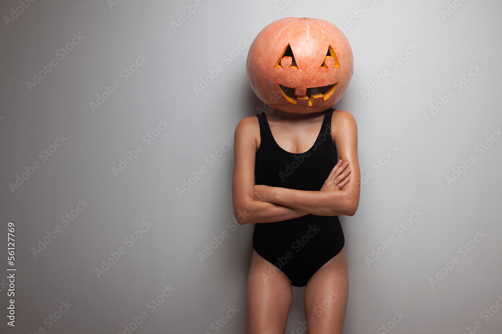 Obraz premium Slim model posing with pumpkin on head. studio