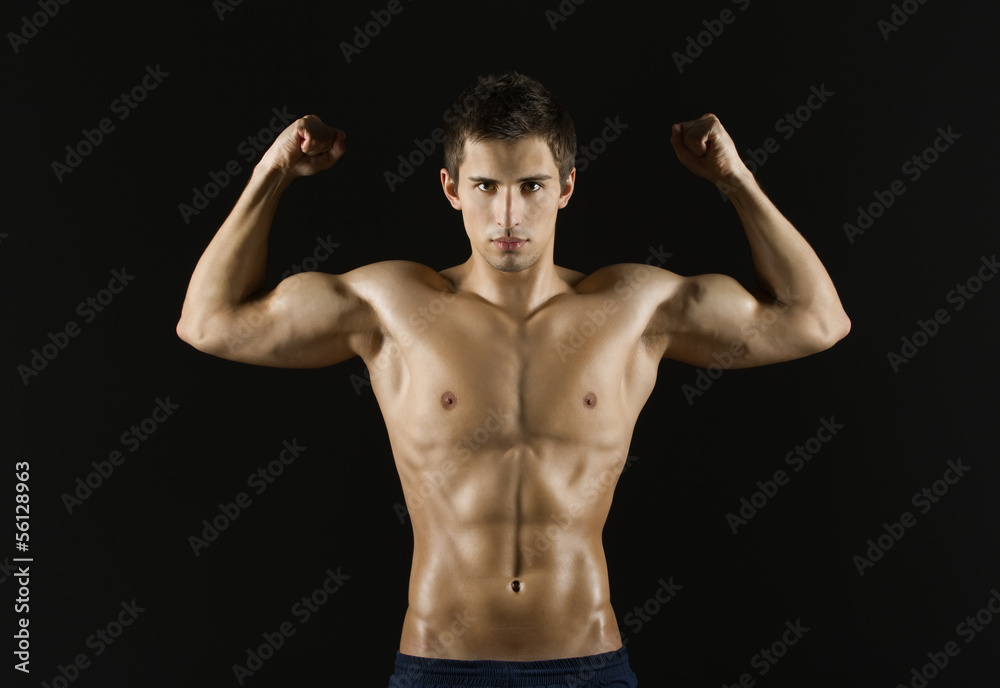 Portrait of naked sportsman with his hands up, isolated on black
