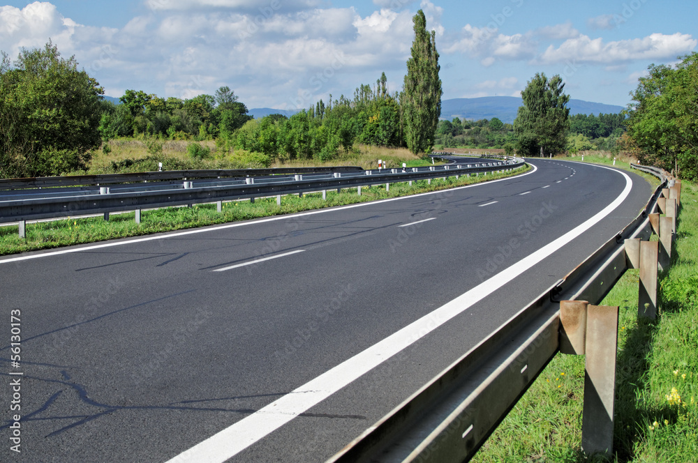Empty highway passing landscape trees