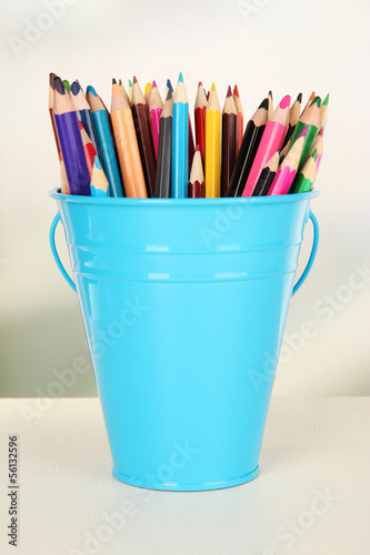 Color bucket with multicolor pencils, on color background
