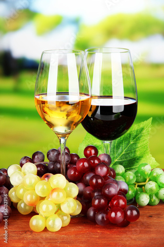 Ripe grapes and glasses of wine  on bright background