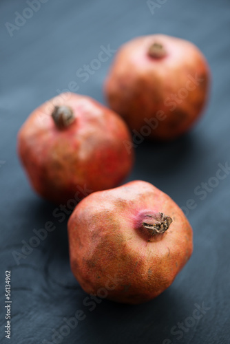 Pomegranates on black wooden background, vertical shot