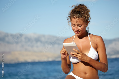 woman using electronic tablet at the beach