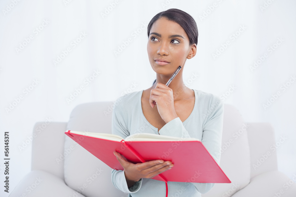 Thoughtful attractive woman sitting on cosy sofa Thoughtful attractive woman sitting on cosy sofa