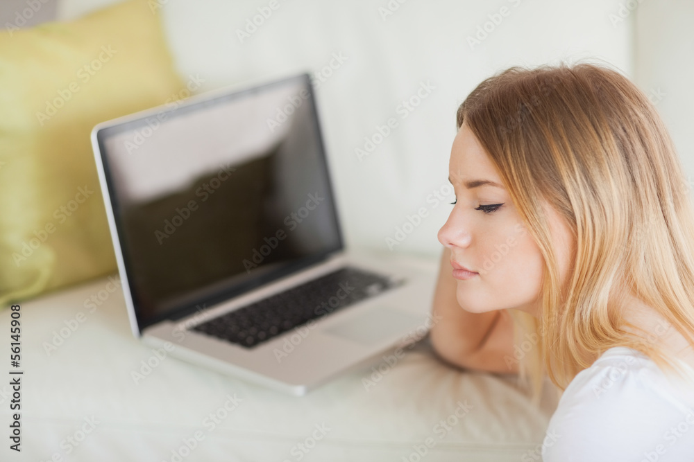Thoughtful woman sitting on floor in front of laptop Thoughtful woman sitting on floor in front of laptop