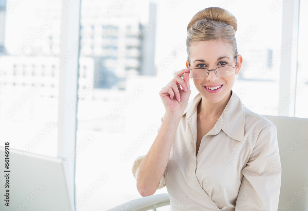 Smiling young blonde businessswoman looking over her glasses Smiling young blonde businessswoman looking over her glasses
