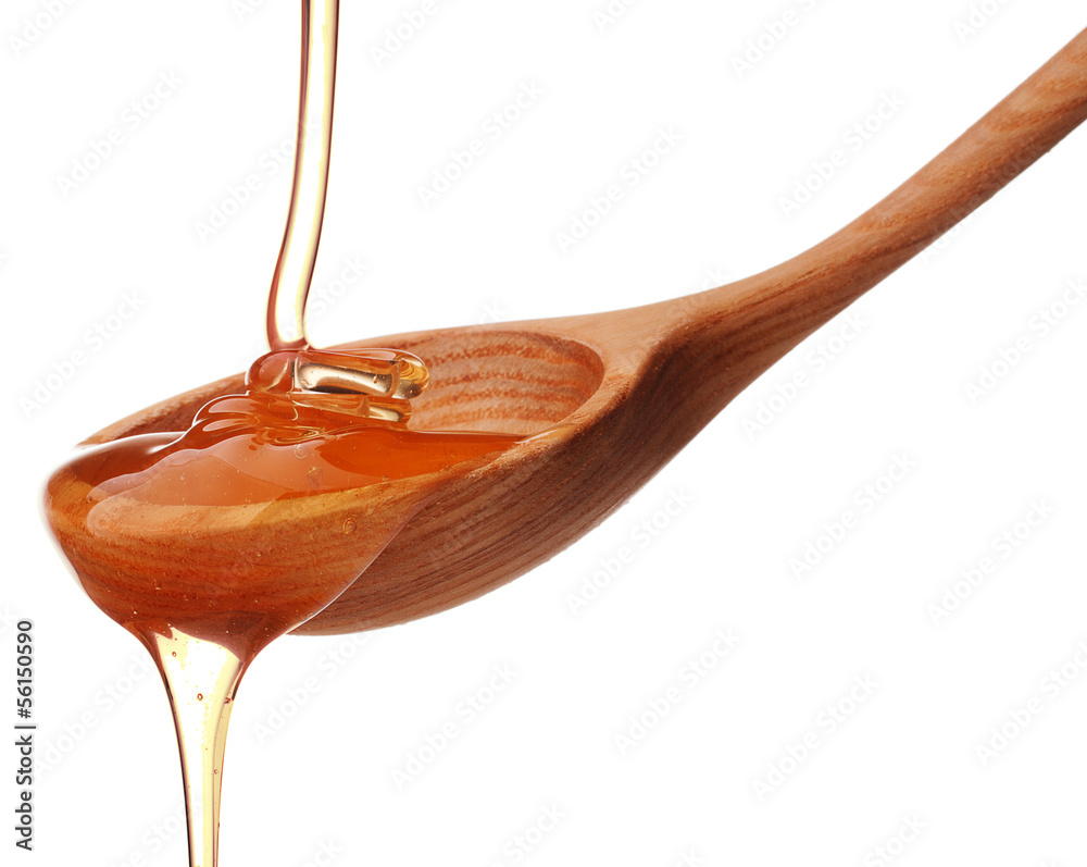 Honey dripping from a wooden honey dipper isolated on white back Honey dripping from a wooden honey dipper isolated on white back