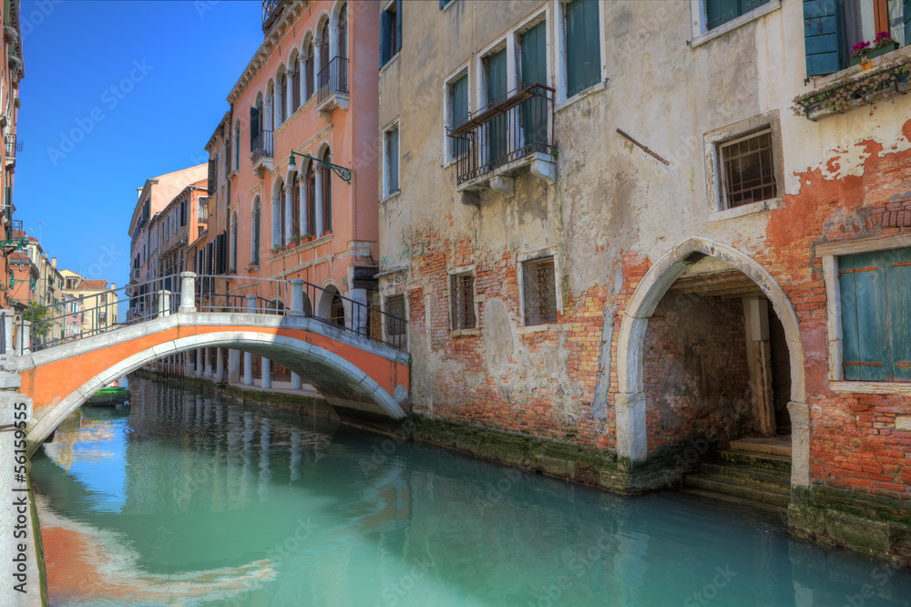 Small bridge over canal and old houses in Venice.