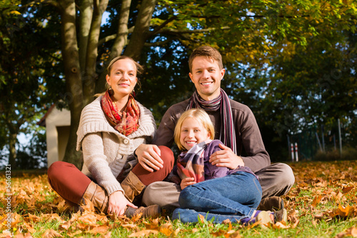 Happy Family outdoors sitting on grass in autumn