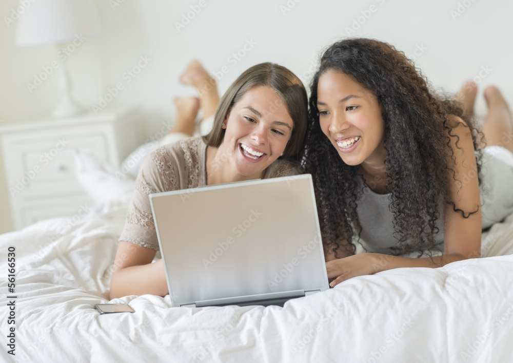 Happy Female Friends Using Laptop In Bed Happy Female Friends Using Laptop In Bed
