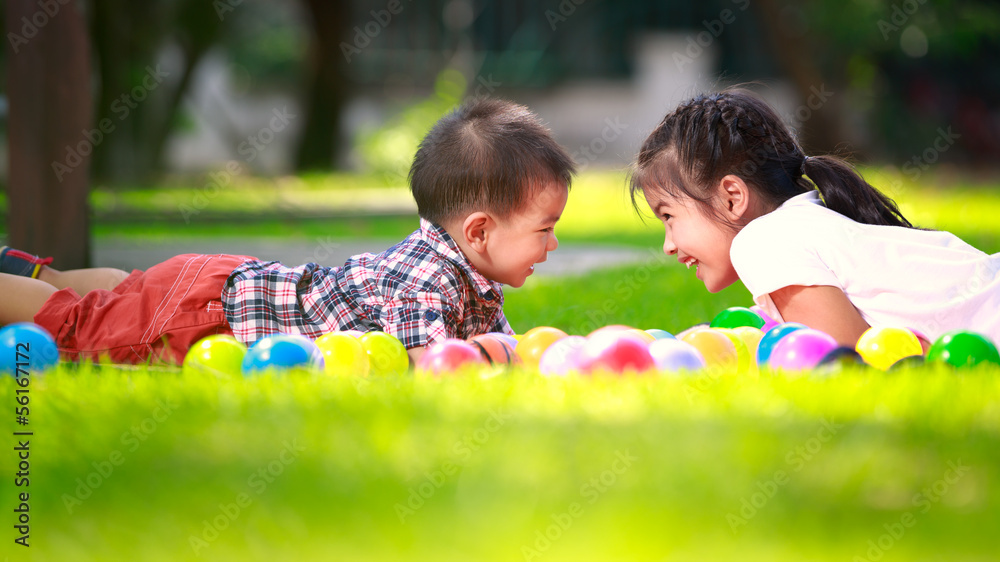 Fototapeta premium Two children are laying on green grass and smile