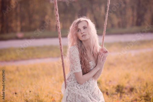 gentle portrait of a beautiful blonde on a swing