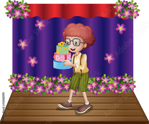A stage with a young boy holding gifts
