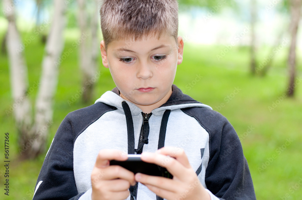 A boy plays on a mobile phone in a park A boy plays on a mobile phone in a park