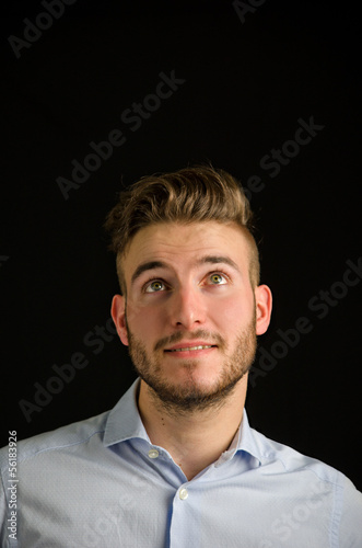 Attractive young man looking up, large copy-space