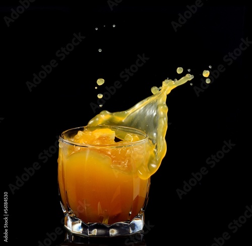 splashing out of a glass with juice on a black background